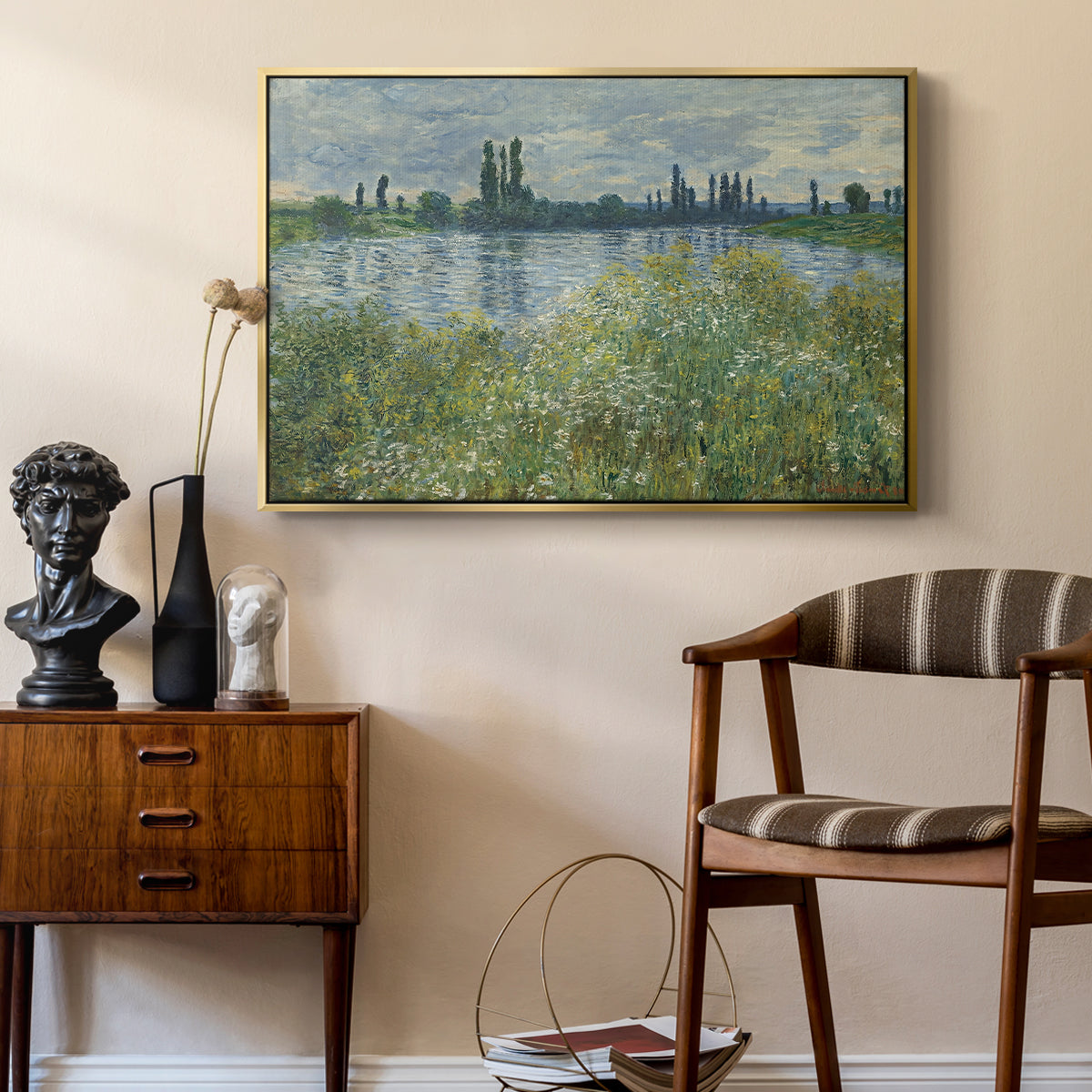 Banks of the Seine, Vétheuil, 1880 by Claude Monet as a gold floater framed canvas featuring a tranquil riverside scene with houses and vegetation, styled above a mid-century console in a contemporary living area.