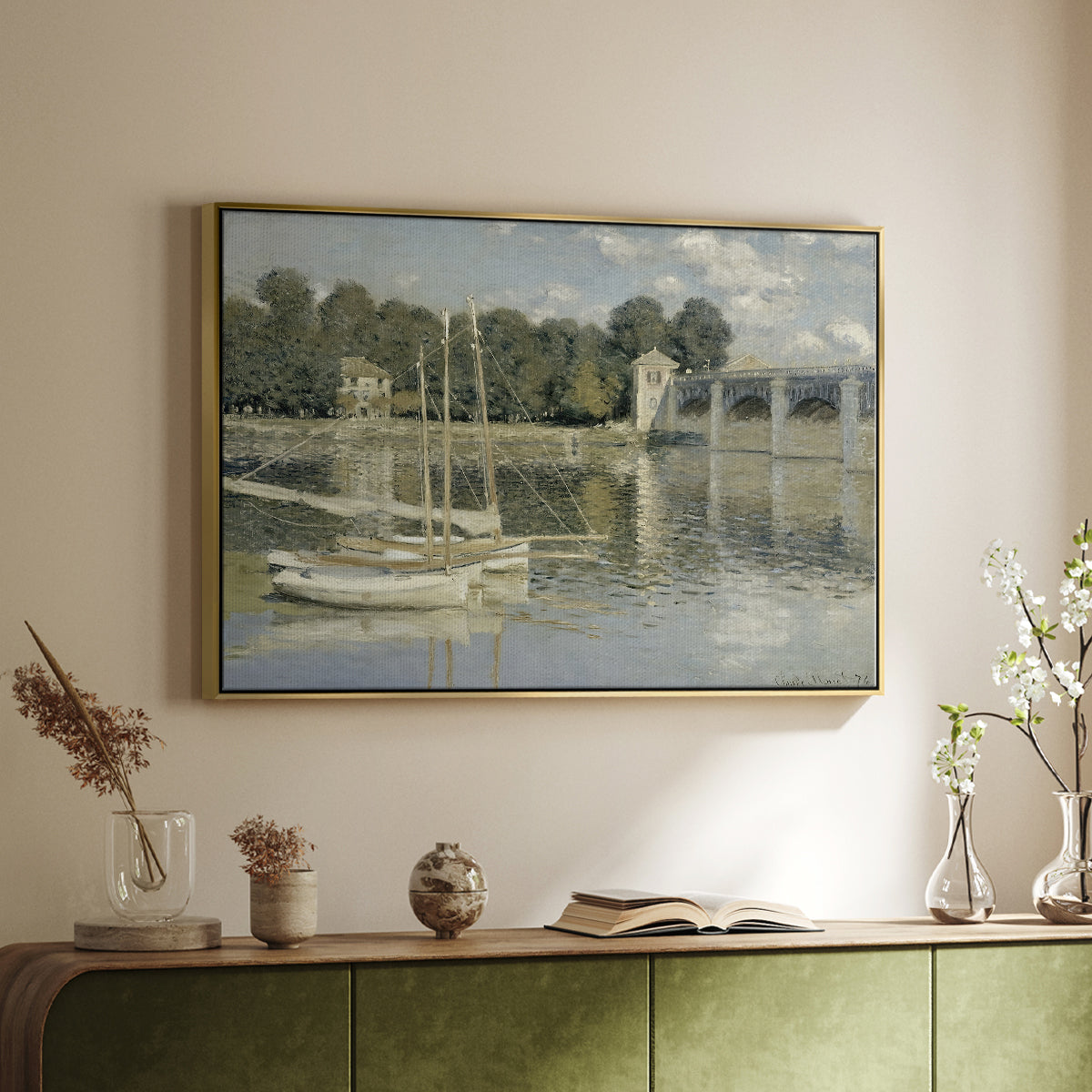 Gold floater framed canvas of The Bridge at Argenteuil, 1874 by Claude Monet, featuring an impressionist river scene with boats passing beneath bridge above a sideboard in a softly lit hallway.
