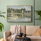 Gold floater framed canvas featuring a riverside view with architecture and nautical activity, displayed above a sofa in a modern living room.