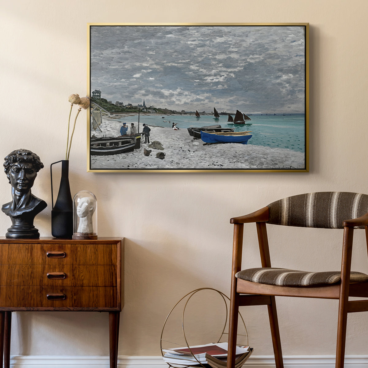 The Beach at Sainte-Adresse, 1867 by Claude Monet as a gold floater framed canvas featuring a coastal landscape with sailboats and visitors on cliffside, styled above a mid-century console in a contemporary living area.