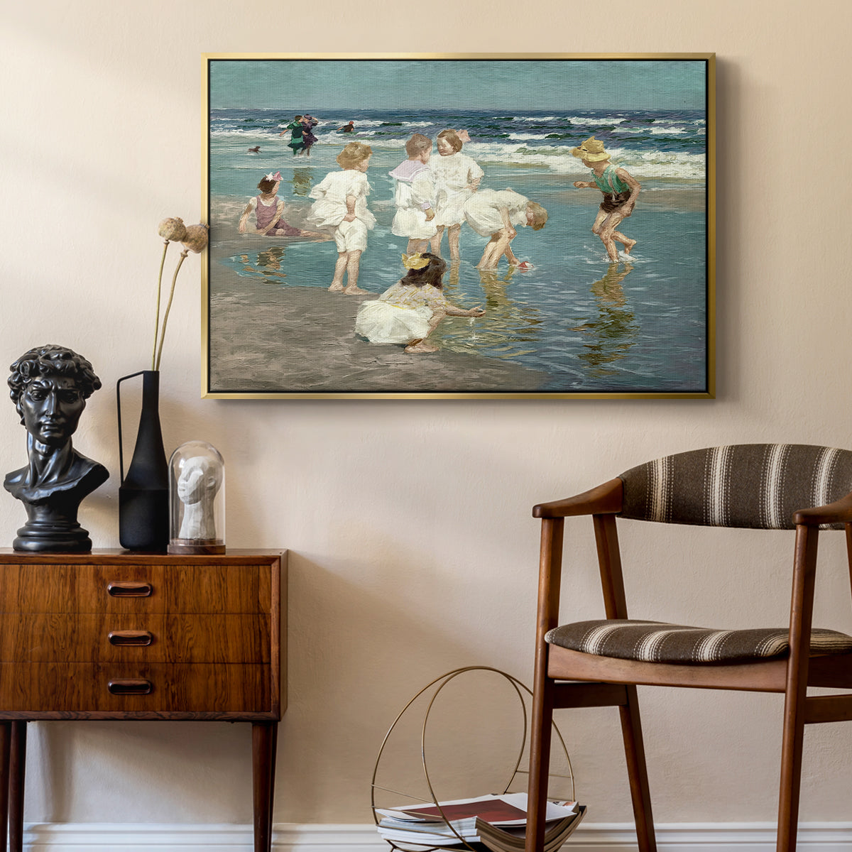 A Holiday, c. 1915 by Edward Henry Potthast as a gold floater framed canvas featuring an impressionist coastal view of families enjoying seaside water, styled above a mid-century console in a contemporary living area.