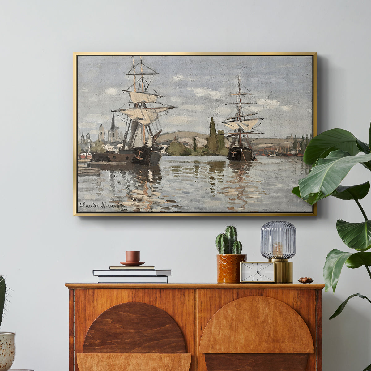 Ships Riding on the Seine at Rouen, 1872 by Claude Monet in a gold floater framed canvas featuring large ships docked along the Seine with masts rising against soft sky, displayed above a wood console cabinet.