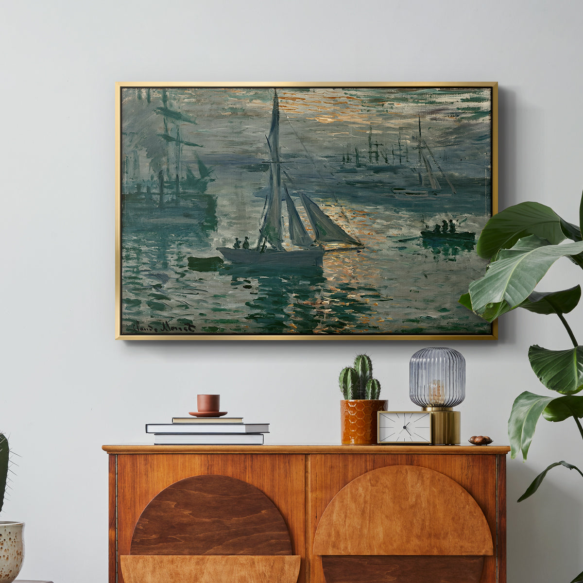 Sunrise (Marine), 1873 by Claude Monet in a gold floater framed canvas featuring a hazy sunrise over harbor with boats silhouetted in soft morning light, displayed above a wood console cabinet.