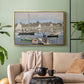 Gold floater framed canvas featuring a tranquil river setting with sailboats and shoreline, displayed above a sofa in a modern living room.