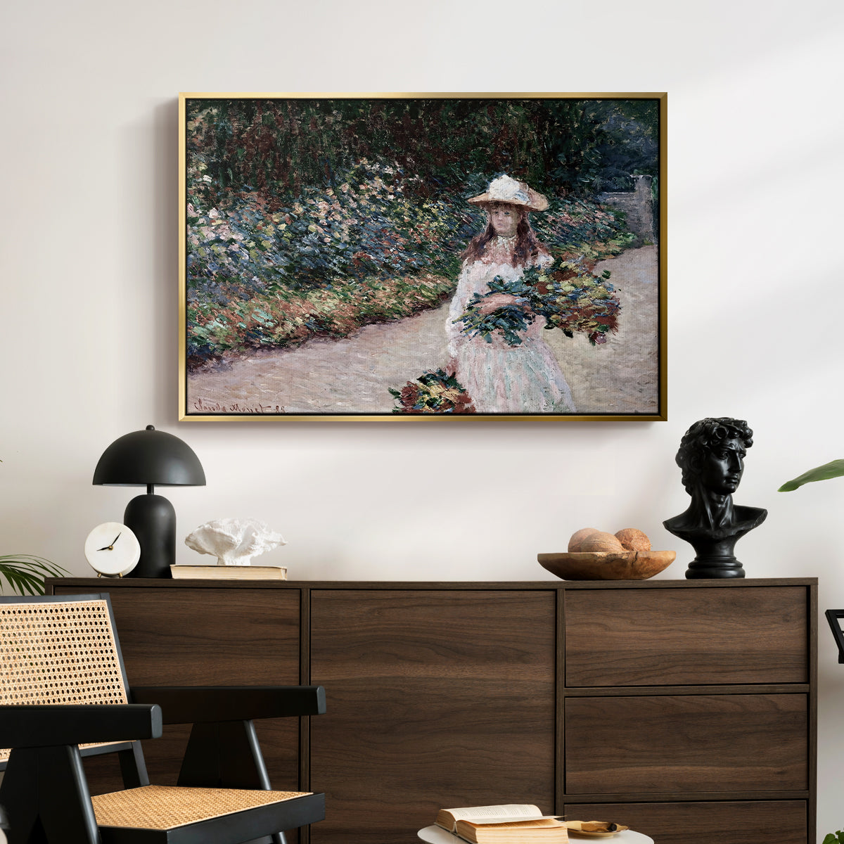 Young Girl in the Garden at Giverny, 1888 by Claude Monet displayed in a gold floater framed canvas above a dark wood credenza in an entryway.