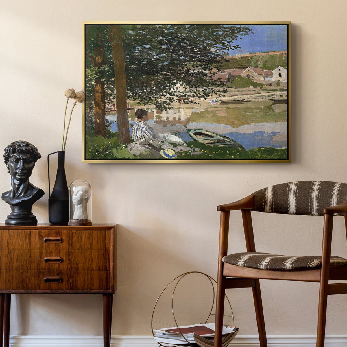 On the Bank of the Seine, Bennecourt, 1868 by Claude Monet as a gold floater framed canvas featuring an impressionist landscape with people relaxing along the Seine, styled above a mid-century console in a contemporary living area.