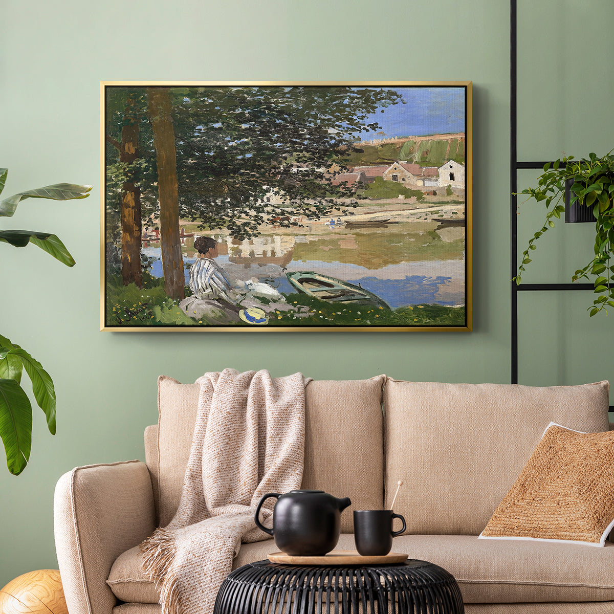Gold floater framed canvas featuring a quiet outdoor setting with figures near river under foliage, displayed above a sofa in a modern living room.