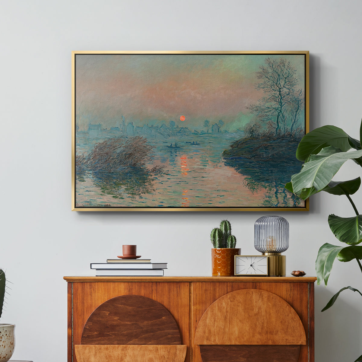 Sunset on the Seine at Lavacourt, Winter Effect, 1880 by Claude Monet in a gold floater framed canvas featuring a glowing sunset over snowy river landscape with soft reflections, displayed above a wood console cabinet.