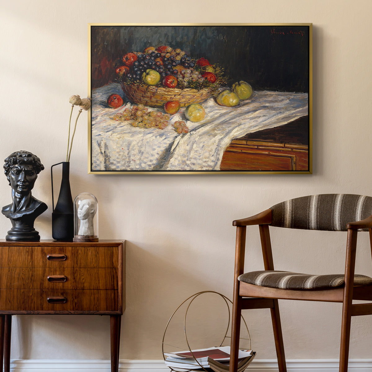 Still Life with Apples and Grapes, 1880 by Claude Monet as a gold floater framed canvas featuring a close-up of apples and grapes in warm tones, styled above a mid-century console in a contemporary living area.