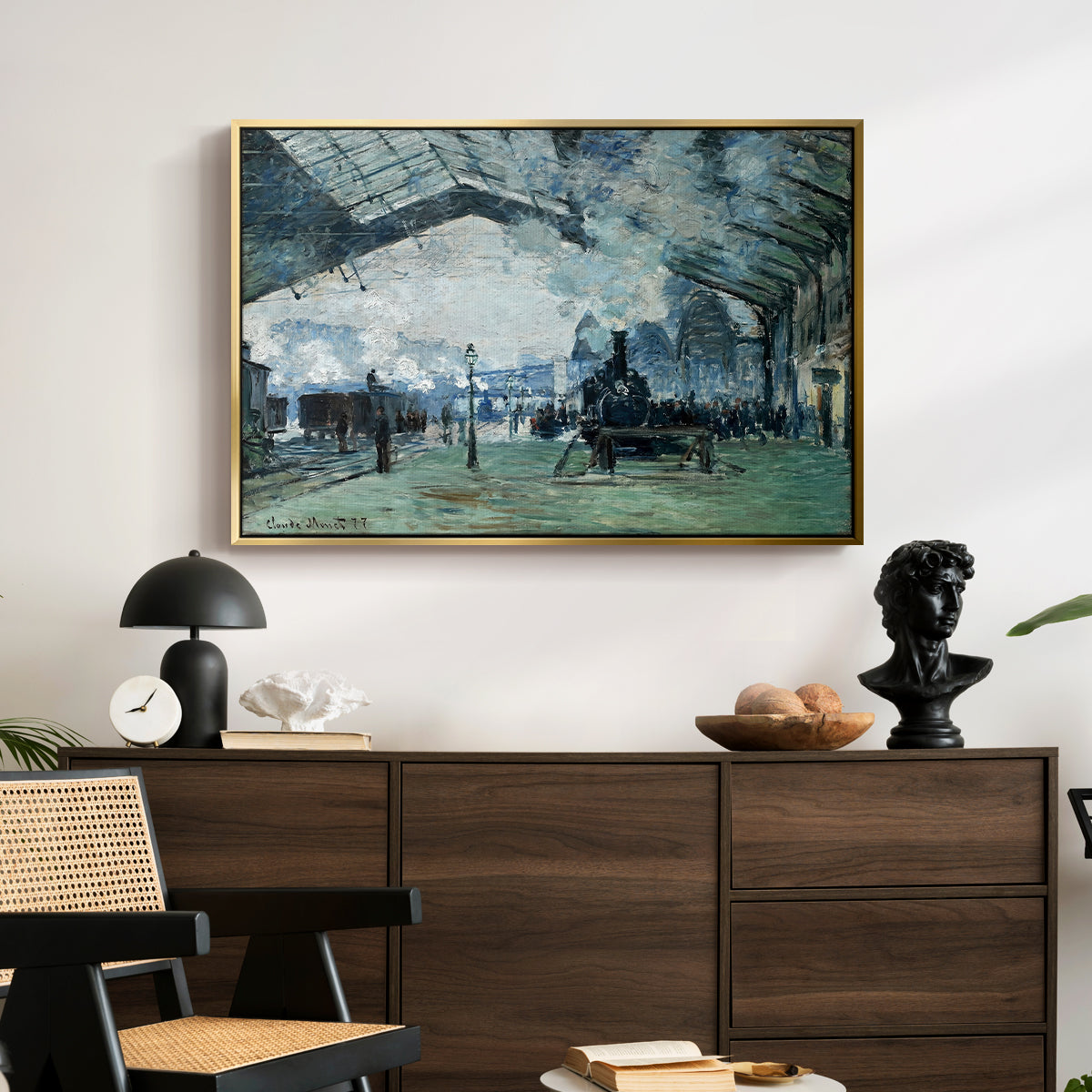 The Saint-Lazare Station, 1877 by Claude Monet displayed in a gold floater framed canvas above a dark wood credenza in an entryway.