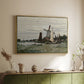 Gold floater framed canvas of Windmill at Zaandam, 1871 by Claude Monet, featuring an impressionist depiction of windmill near riverbank above a sideboard in a softly lit hallway.