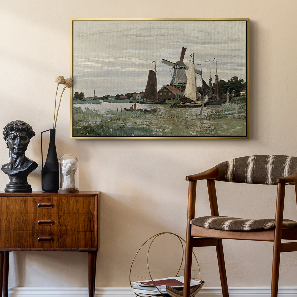 Windmill at Zaandam, 1871 by Claude Monet as a gold floater framed canvas featuring a rustic scene with windmill and reflections in water, styled above a mid-century console in a contemporary living area.