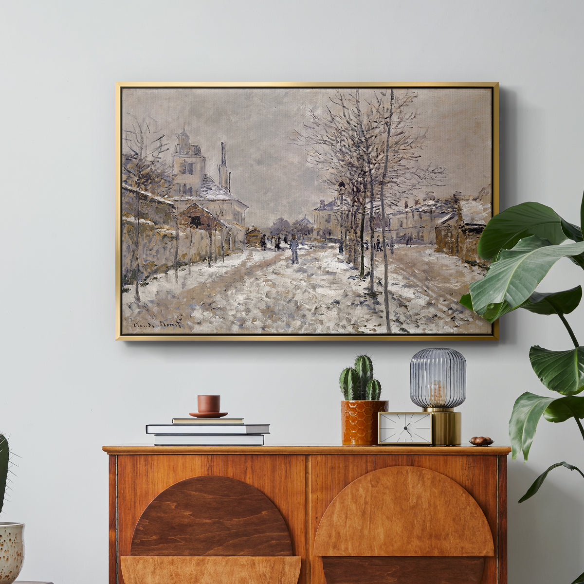 The Boulevard de Pontoise at Argenteuil, Snow Effect, 1875 by Claude Monet in a gold floater framed canvas featuring a snow-covered street lined with trees and buildings under winter sky, displayed above a wood console cabinet.