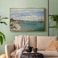 Gold floater framed canvas featuring a nautical scene with boats racing near seaside town, displayed above a sofa in a modern living room.