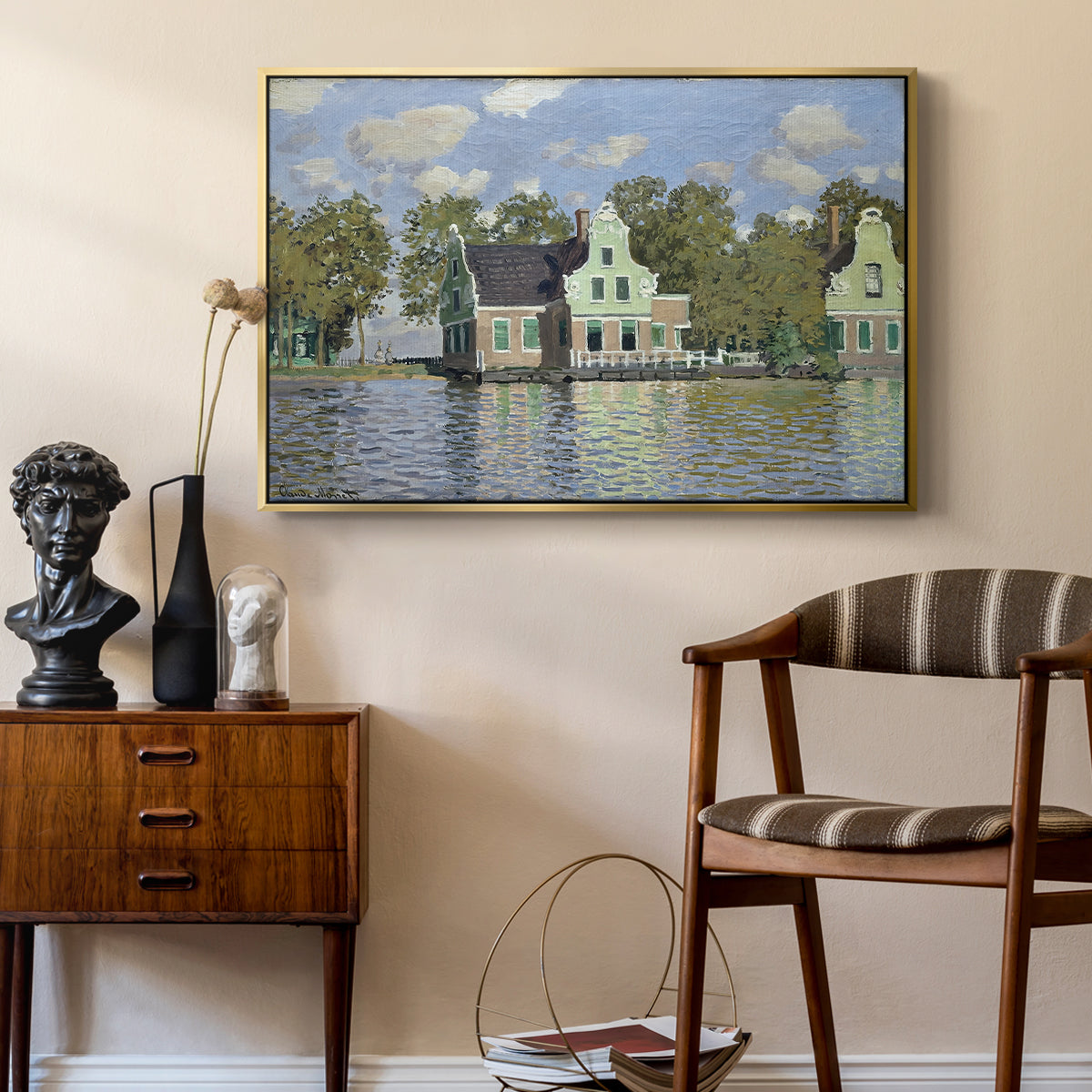Houses on the Zaan River at Zaandam, 1871 by Claude Monet as a gold floater framed canvas featuring a peaceful canal scene with houses mirrored in water, styled above a mid-century console in a contemporary living area.