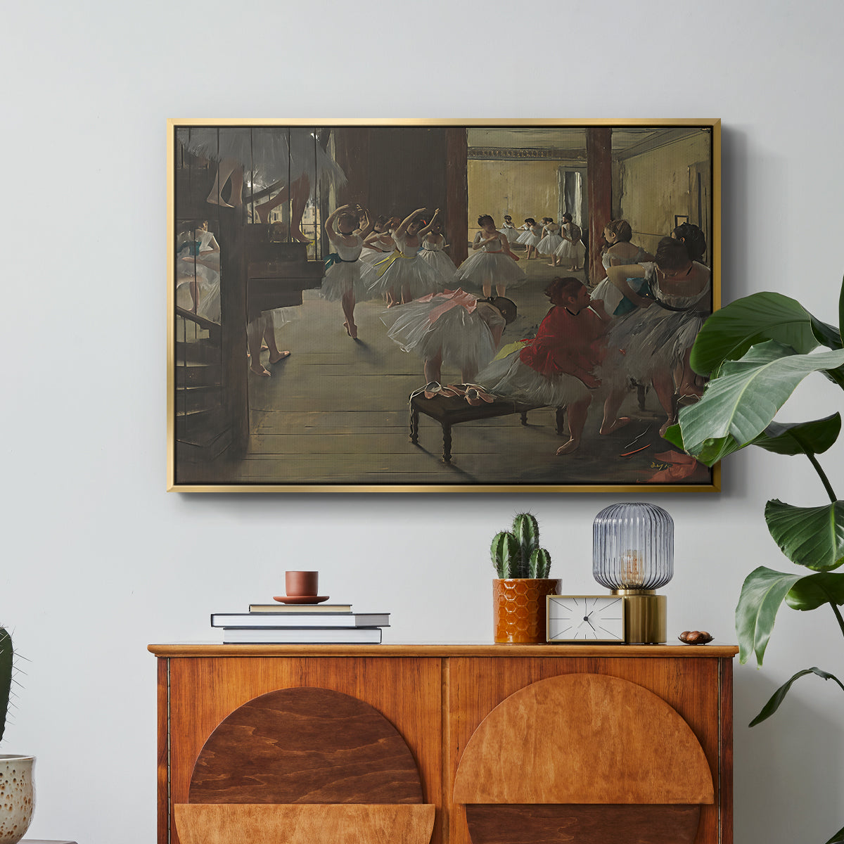 The Dance Class, c. 1873 by Edgar Degas in a gold floater framed canvas featuring ballerinas practicing in studio with instructor observing nearby, displayed above a wood console cabinet.