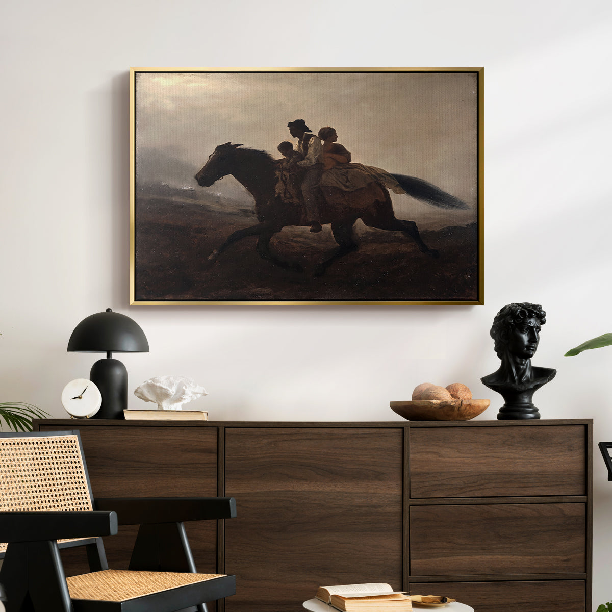 A Ride for Liberty – The Fugitive Slaves, c. 1862 by Eastman Johnson displayed in a gold floater framed canvas above a dark wood credenza in an entryway.