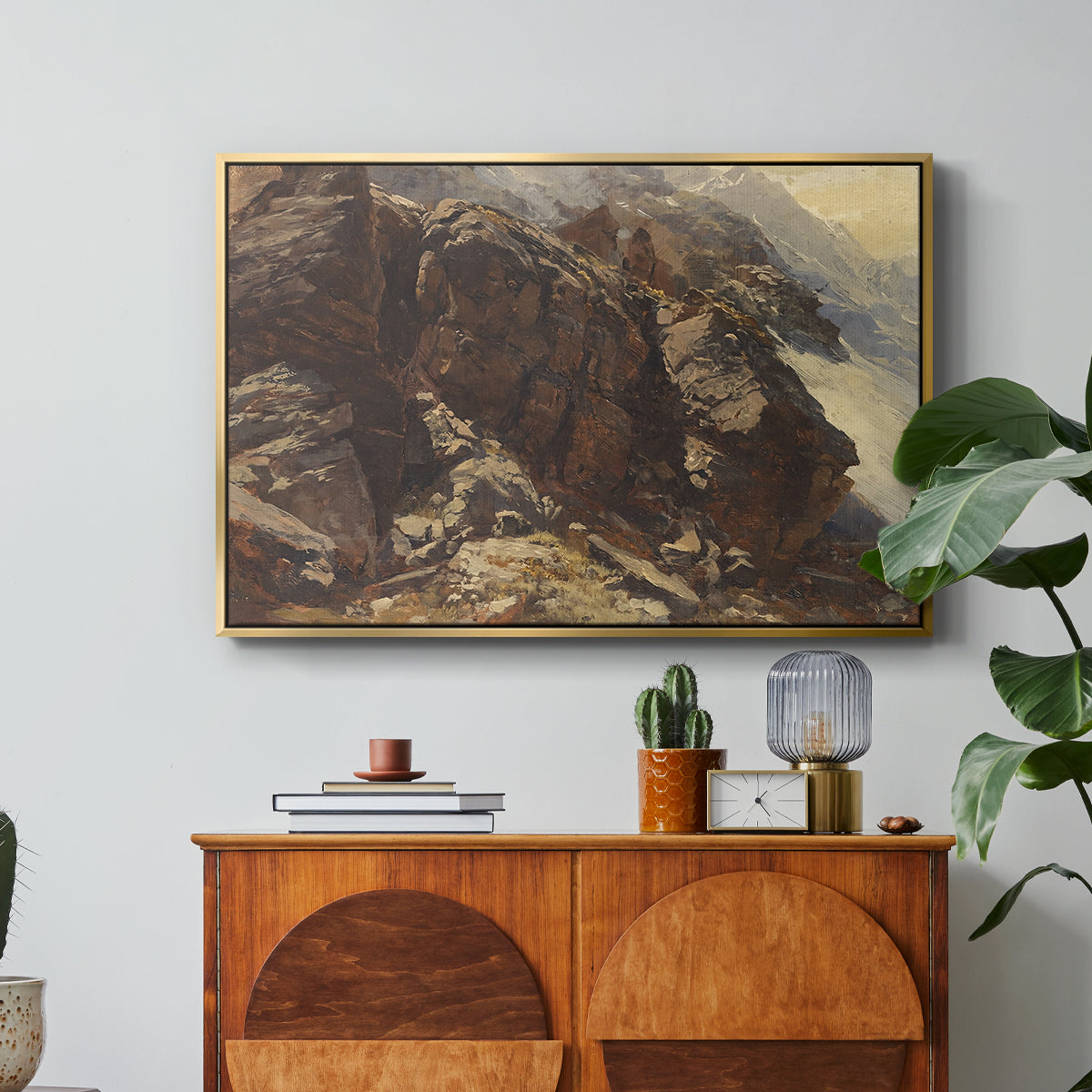 High Mountain Study, c. 1870 by Edward Theodore Compton in a gold floater framed canvas featuring a rocky alpine terrain with steep slopes and distant mountain peaks, displayed above a wood console cabinet.