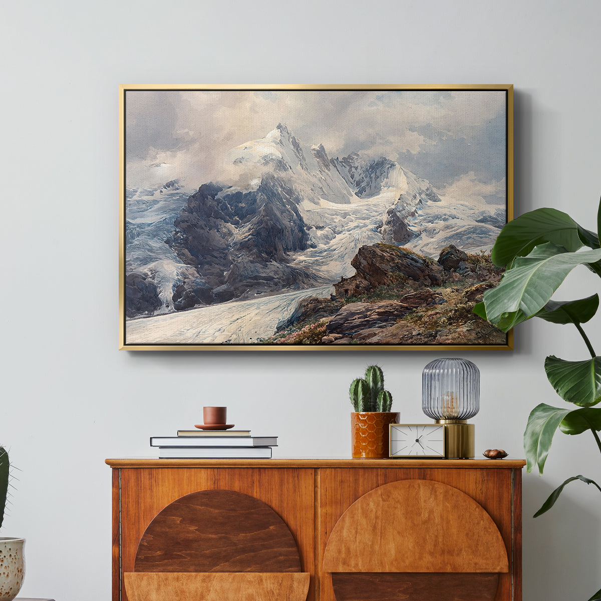 The Grossglockner, 1880 by Edward Theodore Compton in a gold floater framed canvas featuring a towering mountain peak rising above rocky alpine landscape, displayed above a wood console cabinet.