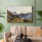 Gold floater framed canvas featuring a scenic mountain view with dramatic elevation and depth, displayed above a sofa in a modern living room.