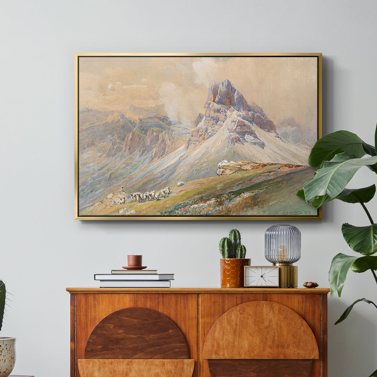 From the Dolomites, 1904 by Edward Theodore Compton in a gold floater framed canvas featuring dramatic Dolomite mountain peaks rising above rugged terrain, displayed above a wood console cabinet.