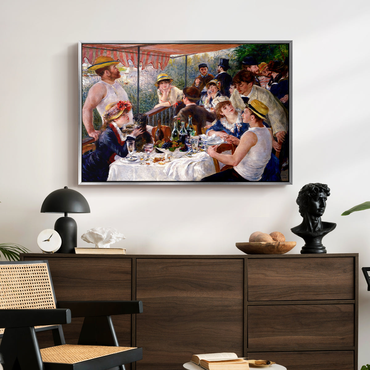 Luncheon of the Boating Party (Le Déjeuner des canotiers), 1880-1881 by Pierre-Auguste Renoir displayed in a silver floater framed canvas above a dark wood credenza in an entryway.