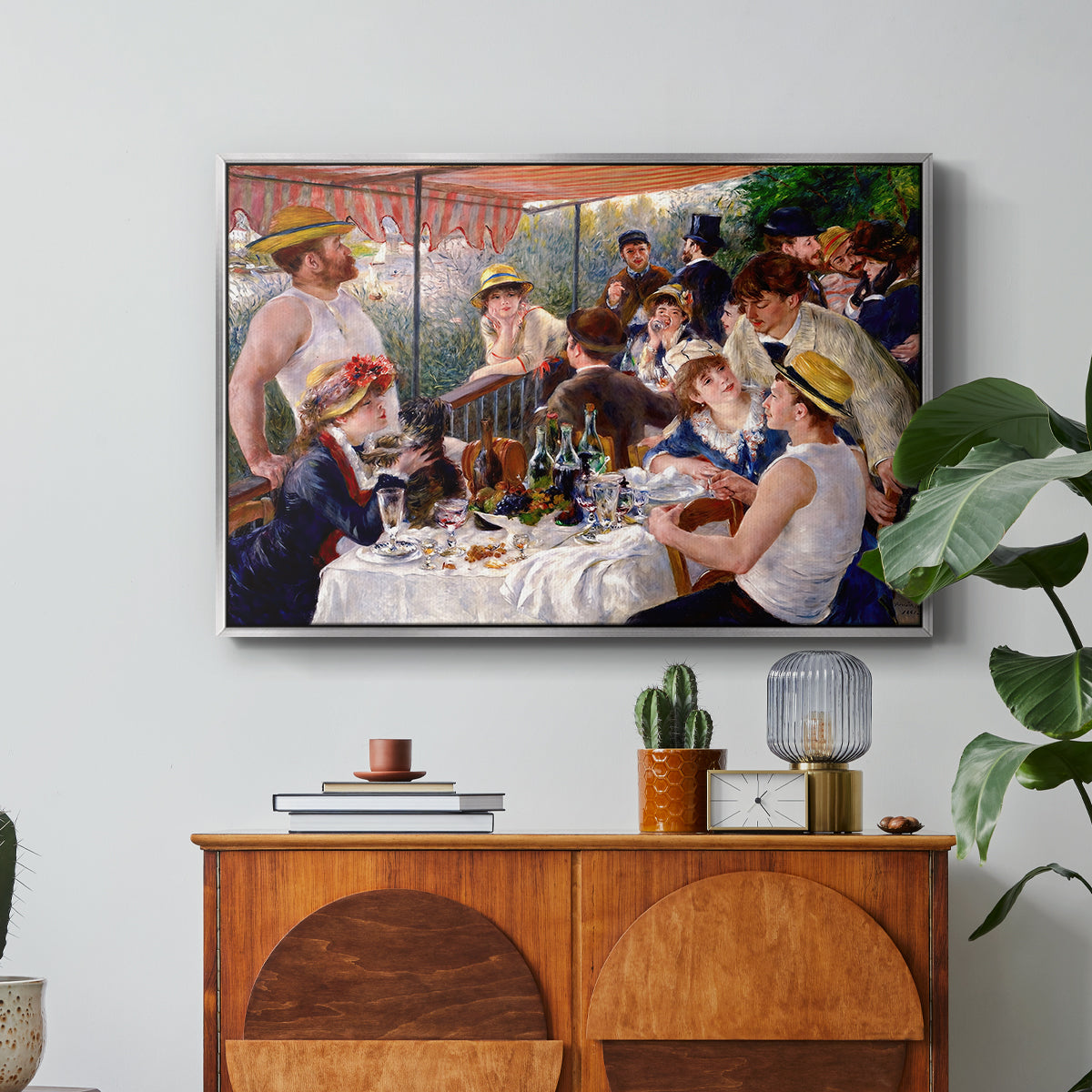 Luncheon of the Boating Party (Le Déjeuner des canotiers), 1880-1881 by Pierre-Auguste Renoir in a silver floater framed canvas featuring a group of elegantly dressed people dining together on a sunlit balcony overlooking the river, displayed above a wood console cabinet.