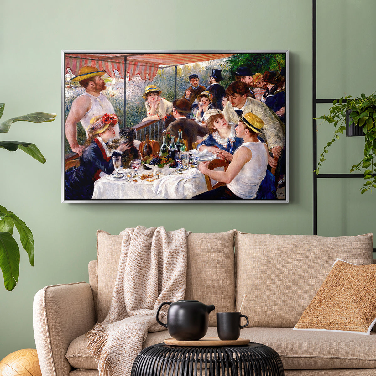 Silver floater framed canvas featuring a social dining scene with figures seated around table on riverside terrace, displayed above a sofa in a modern living room.