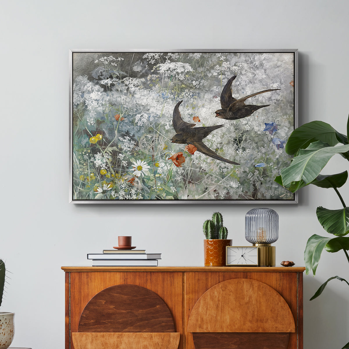 Common Swifts, 1886 by Bruno Liljefors in a silver floater framed canvas featuring a flock of birds in flight soaring across open sky above landscape, displayed above a wood console cabinet.