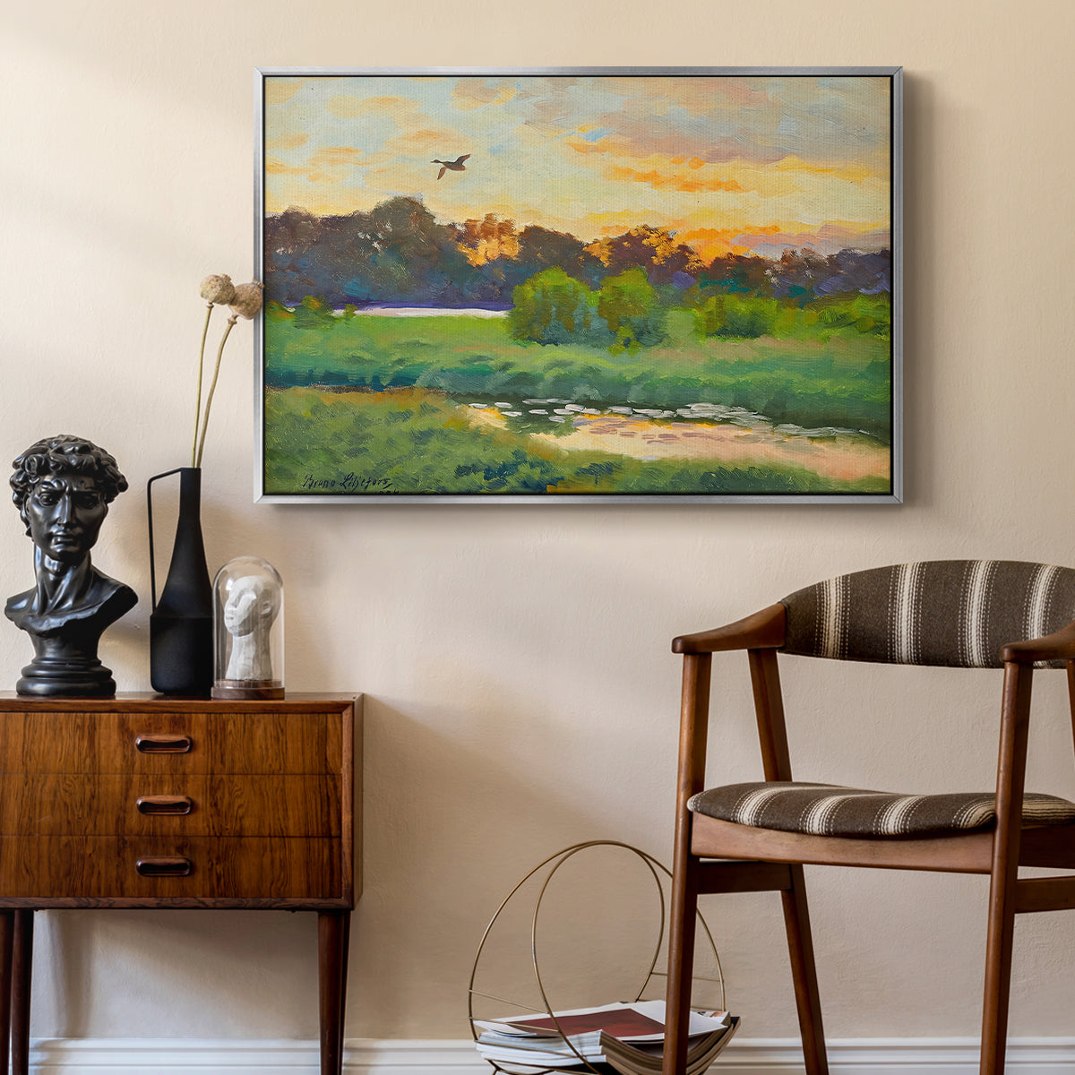 Flying Duck at Sunset, 1924 by Bruno Liljefors as a silver floater framed canvas featuring a wild duck gliding through a golden sunset sky, styled above a mid-century console in a contemporary living area.