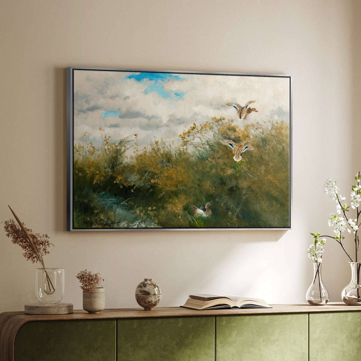 Silver floater framed canvas of Wild Ducks (Grasänder), 1890 by Bruno Liljefors, featuring a wildlife scene of ducks walking through tall grass beside water above a sideboard in a softly lit hallway.