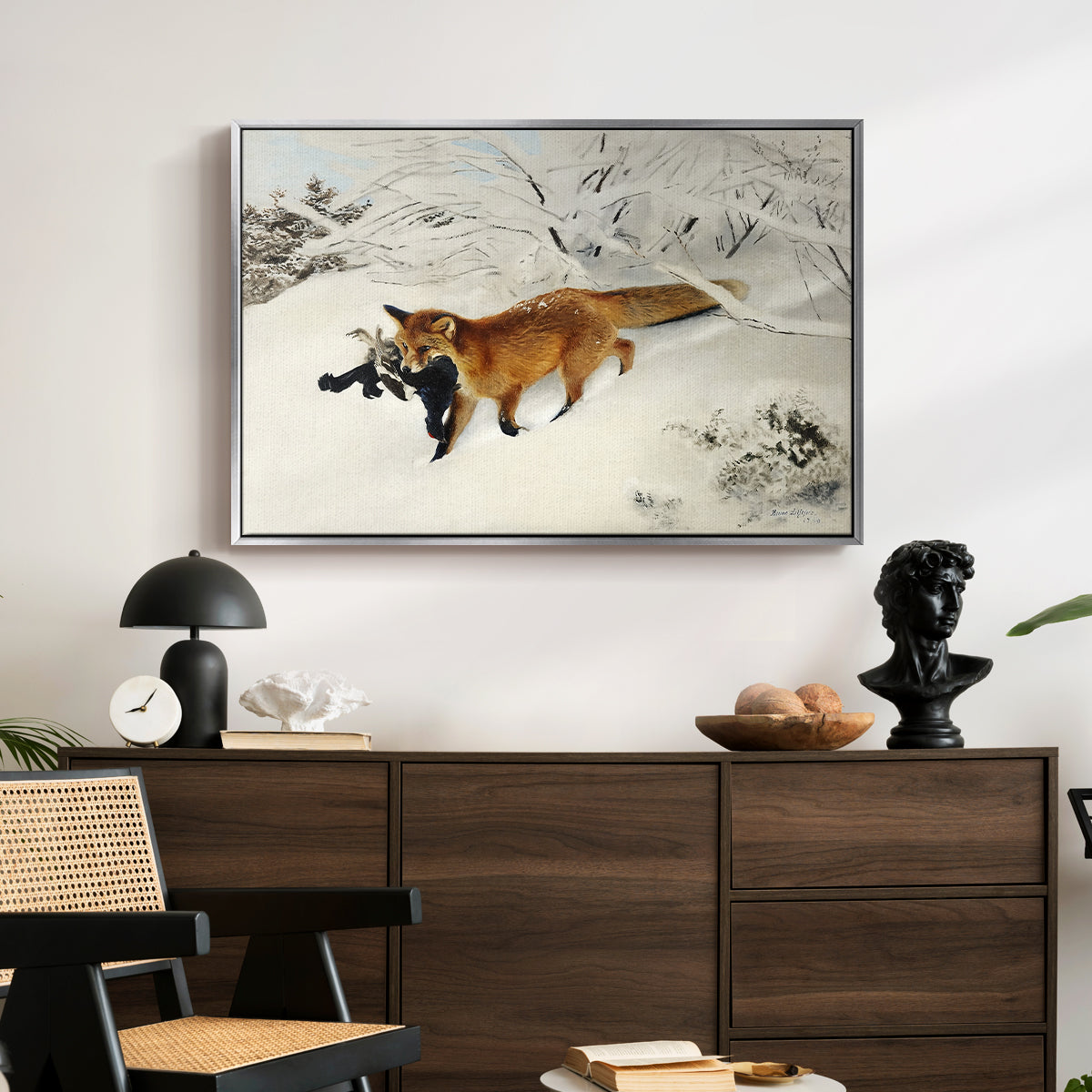 Fox in Snow Landscape, 1900 by Bruno Liljefors displayed in a silver floater framed canvas above a dark wood credenza in an entryway.