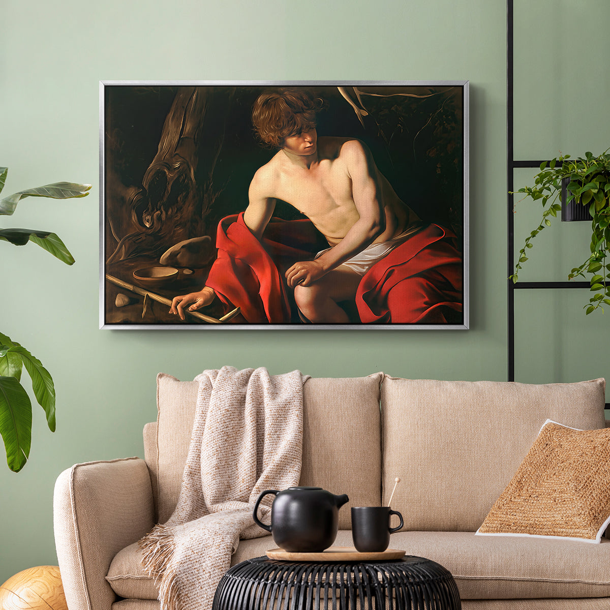 Silver floater framed canvas featuring a contemplative religious figure in rustic wilderness environment, displayed above a sofa in a modern living room.