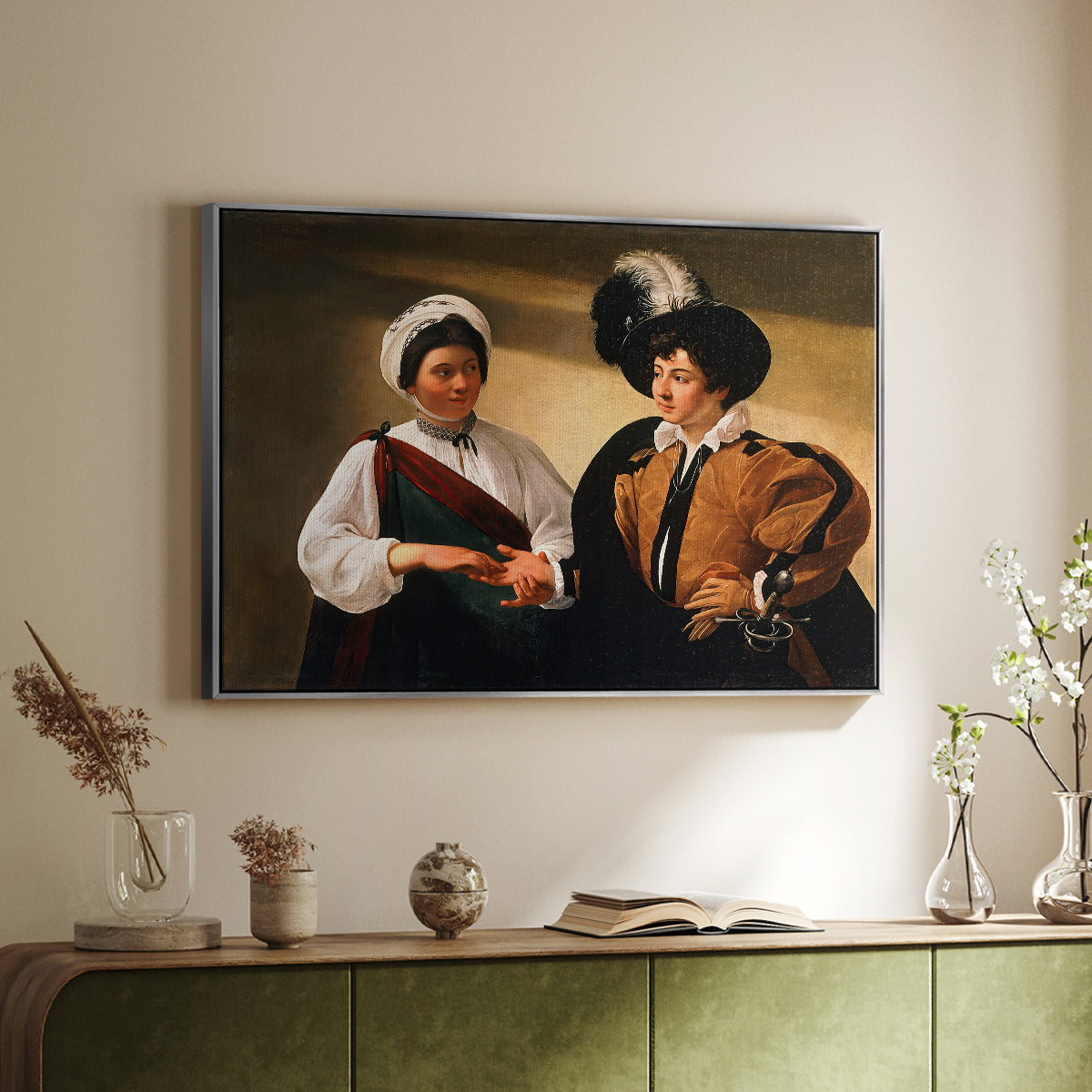 Silver floater framed canvas of The Fortune Teller (Louvre Version), c. 1595 by Caravaggio, featuring a fortune teller examining hand of man as she slyly removes his ring above a sideboard in a softly lit hallway.