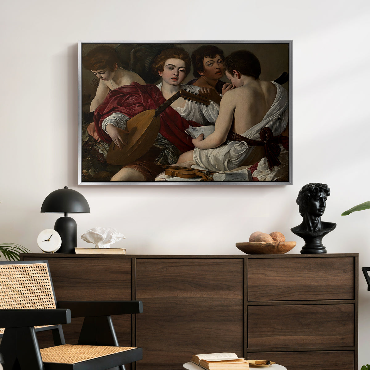 The Musicians, c. 1595 by Caravaggio displayed in a silver floater framed canvas above a dark wood credenza in an entryway.