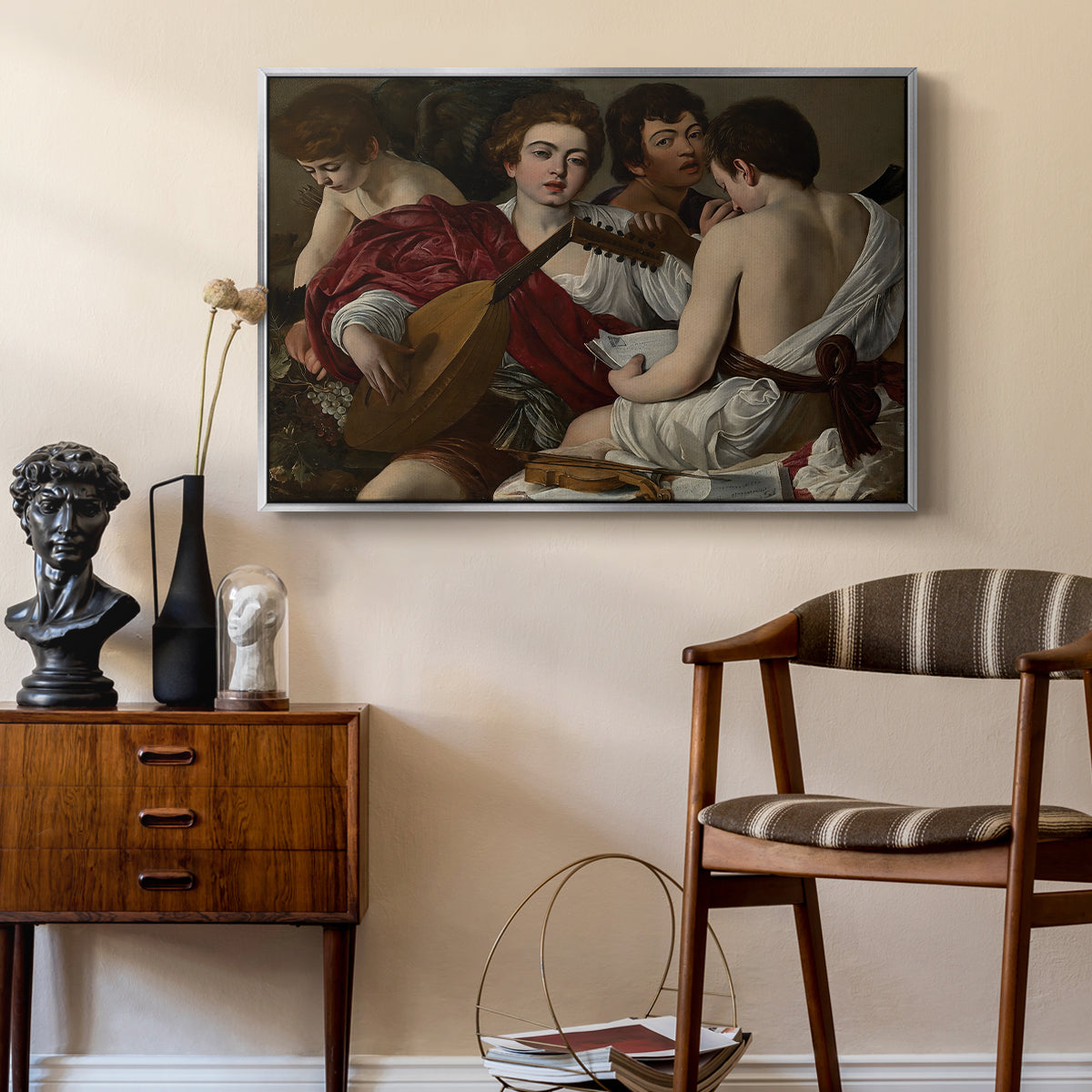 The Musicians, c. 1595 by Caravaggio as a silver floater framed canvas featuring an intimate scene of youths making music with sheet music and instruments, styled above a mid-century console in a contemporary living area.