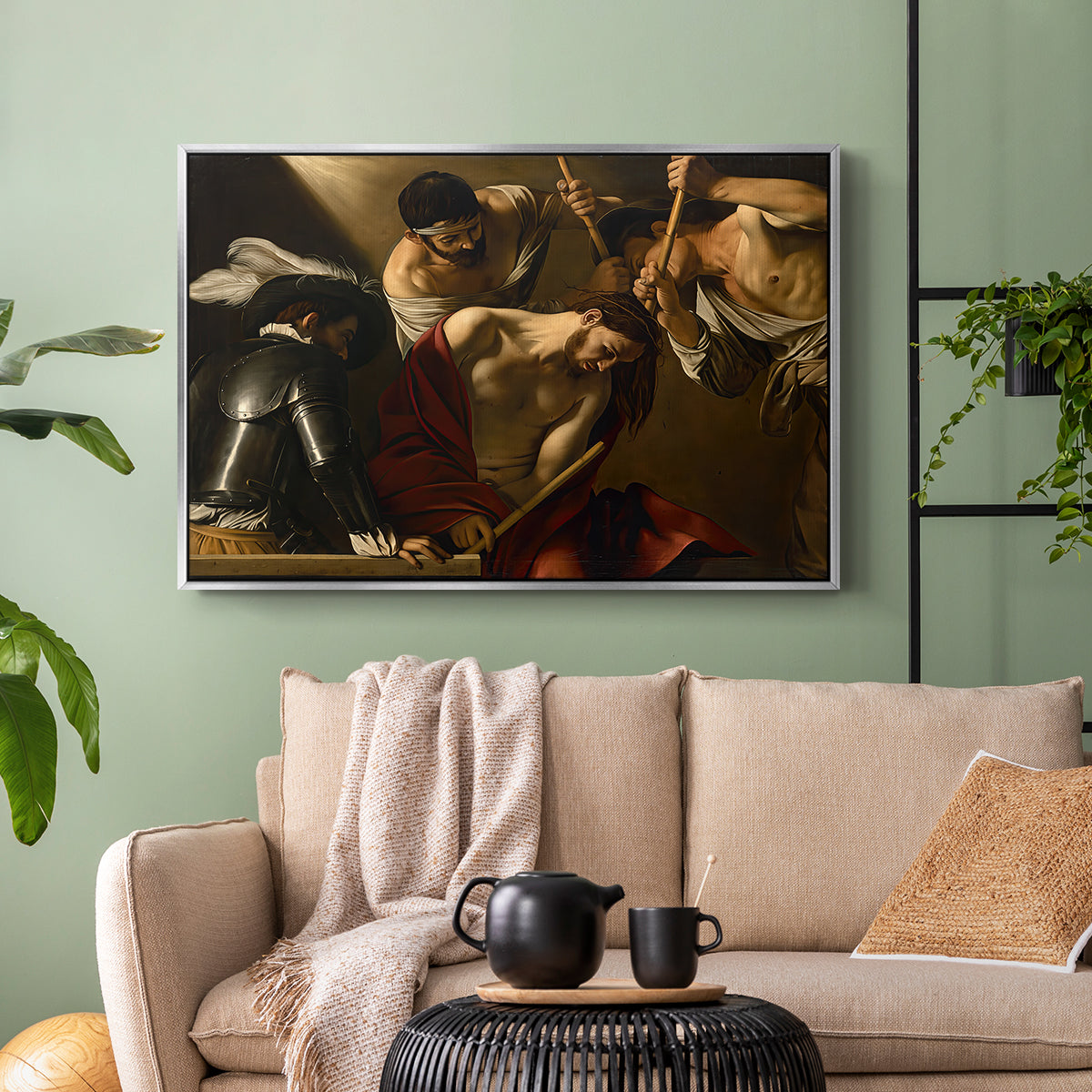 Silver floater framed canvas featuring an intense religious composition with strong shadow and physical struggle, displayed above a sofa in a modern living room.