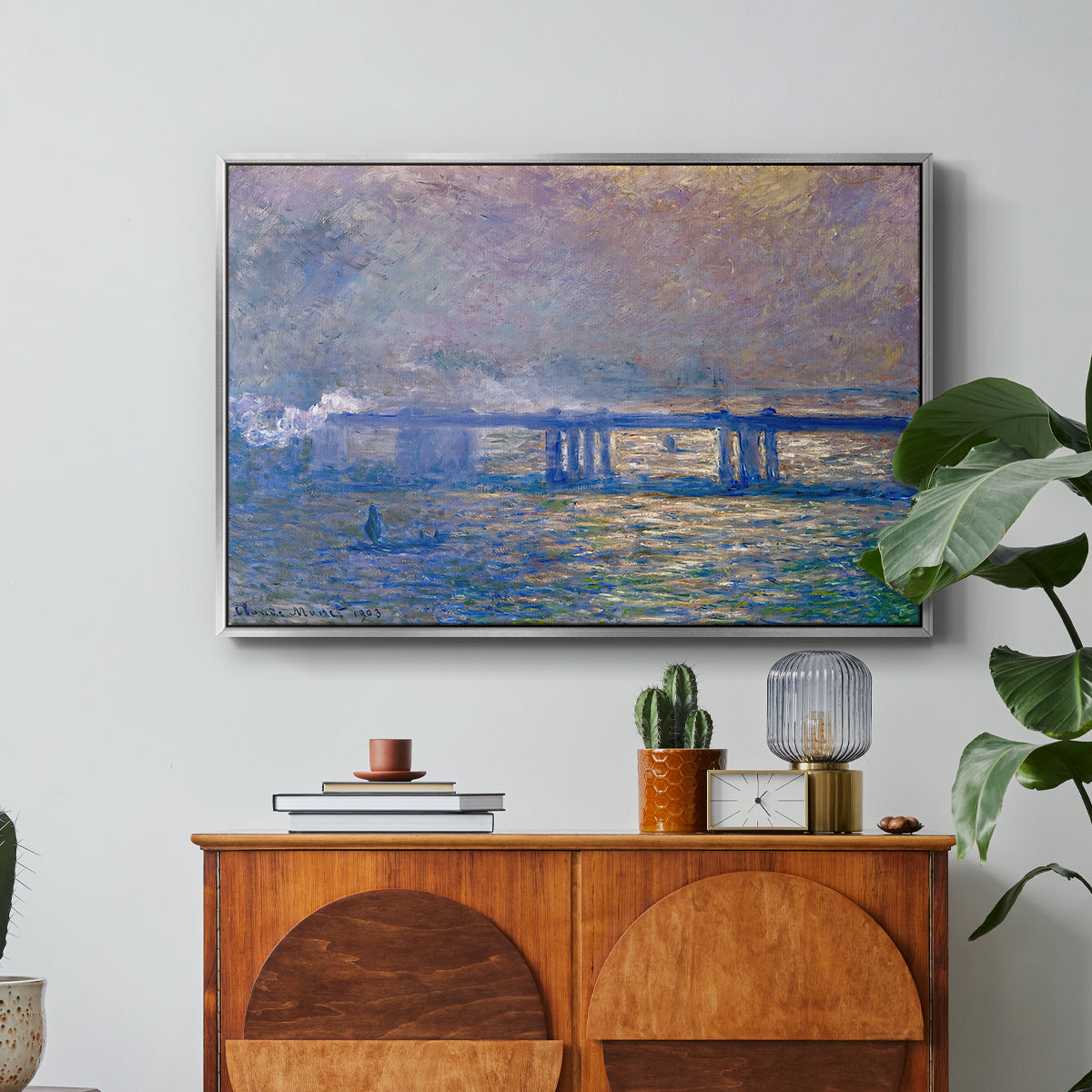 Charing Cross Bridge, 1903 by Claude Monet in a silver floater framed canvas featuring an impressionist view of bridge stretching across river with soft light and haze, displayed above a wood console cabinet.