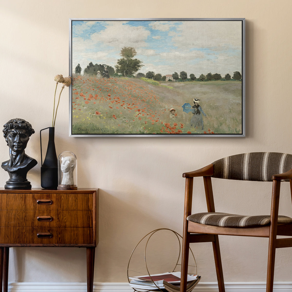 The Poppy Field near Argenteuil, 1873 by Claude Monet as a silver floater framed canvas featuring a bright meadow filled with poppies under open sky, styled above a mid-century console in a contemporary living area.