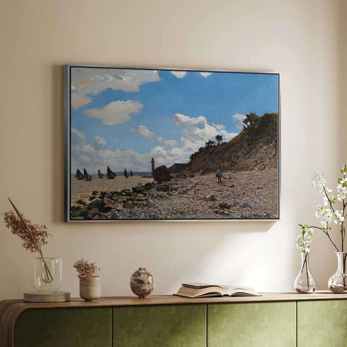 Silver floater framed canvas of The Beach at Honfleur, 1864 by Claude Monet, featuring an impressionist seaside with people and sailboats under bright sky above a sideboard in a softly lit hallway.