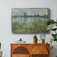 Banks of the Seine, Vétheuil, 1880 by Claude Monet in a silver floater framed canvas featuring a riverbank landscape with water, trees, and distant village buildings, displayed above a wood console cabinet.