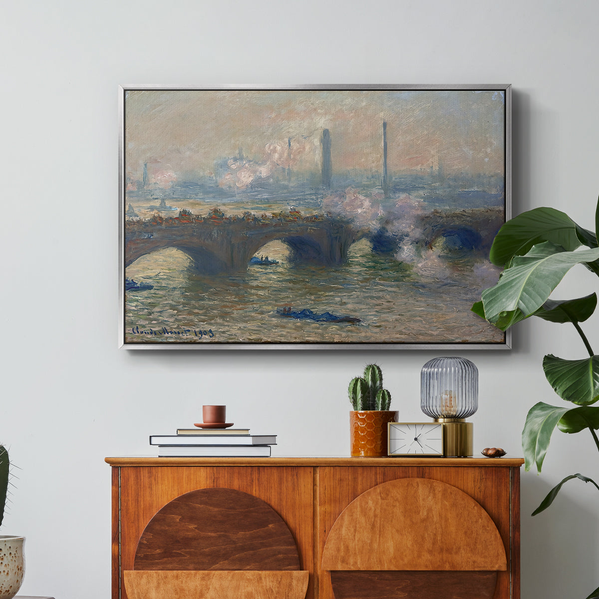 Waterloo Bridge, Gray Day, 1903 by Claude Monet in a silver floater framed canvas featuring a muted cityscape of bridge spanning river under overcast sky, displayed above a wood console cabinet.
