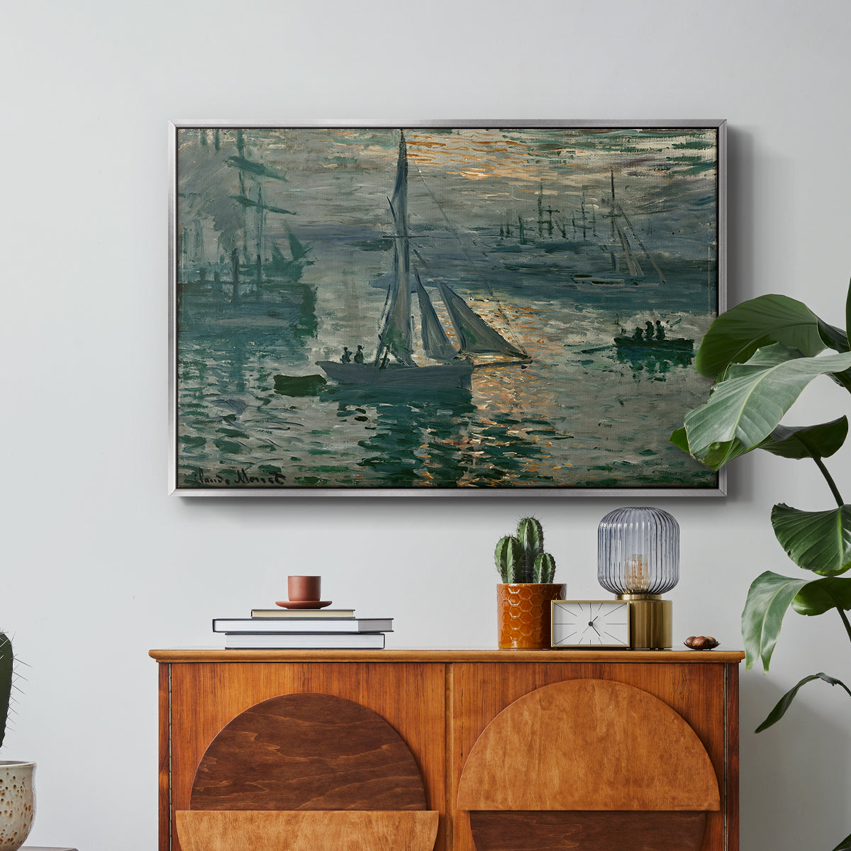 Sunrise (Marine), 1873 by Claude Monet in a silver floater framed canvas featuring a hazy sunrise over harbor with boats silhouetted in soft morning light, displayed above a wood console cabinet.