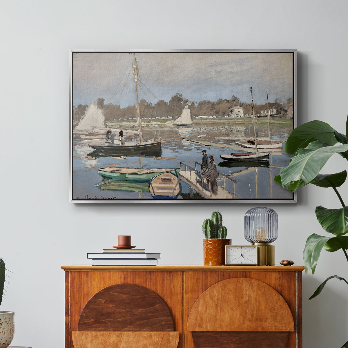 The Basin at Argenteuil, 1874 by Claude Monet in a silver floater framed canvas featuring sailboats gathered in calm basin with reflections on water, displayed above a wood console cabinet.