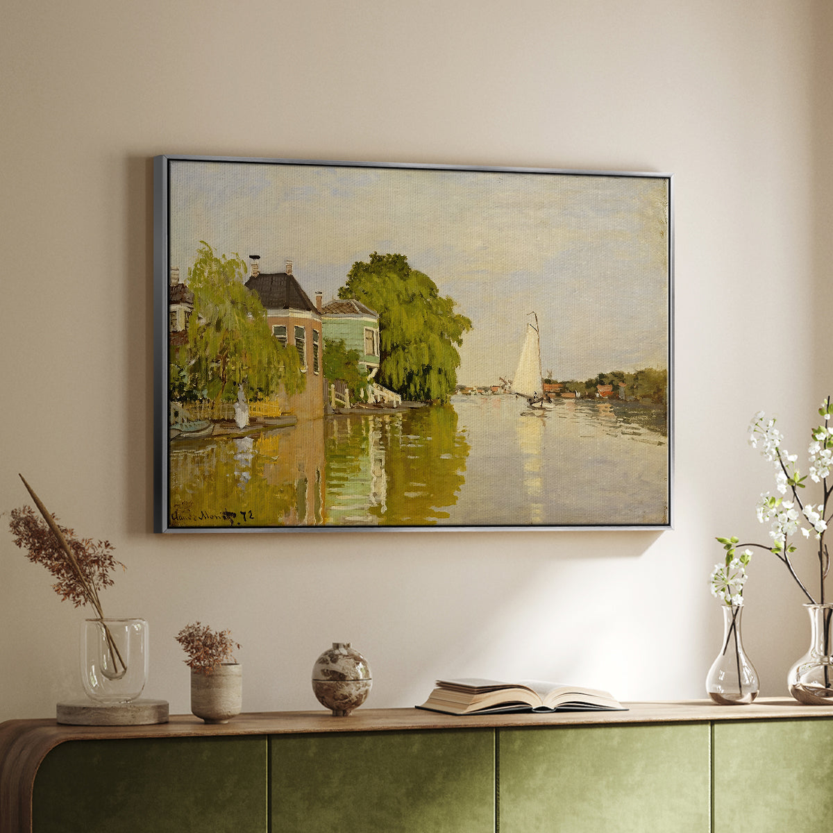 Silver floater framed canvas of Houses on the Achterzaan, 1871 by Claude Monet, featuring riverside homes with trees and mirrored reflections in water above a sideboard in a softly lit hallway.