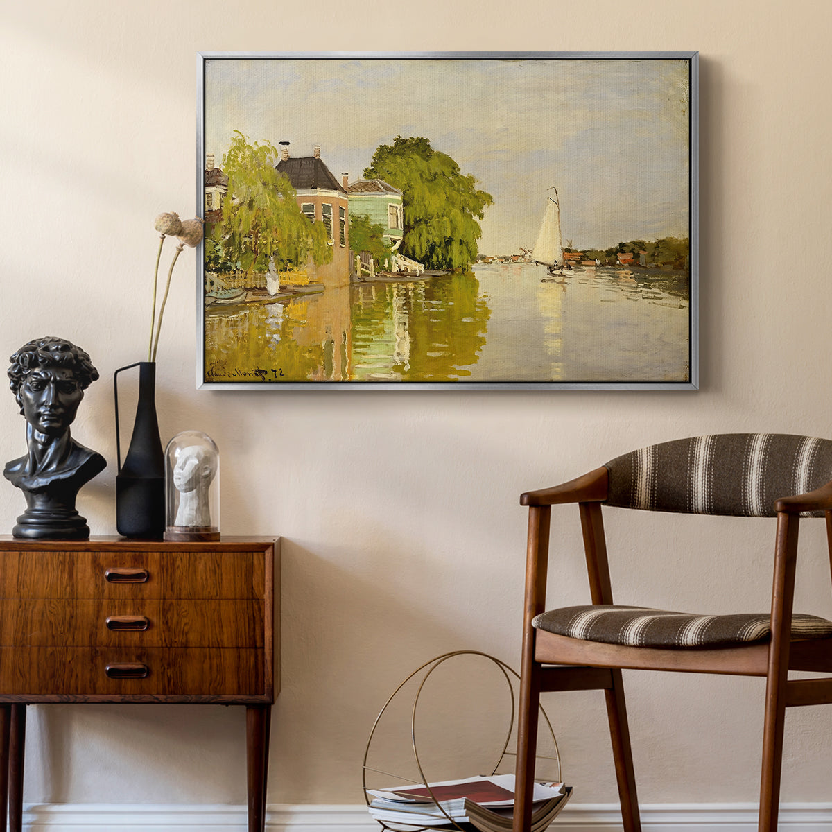 Houses on the Achterzaan, 1871 by Claude Monet as a silver floater framed canvas featuring an impressionist landscape with buildings along quiet canal, styled above a mid-century console in a contemporary living area.