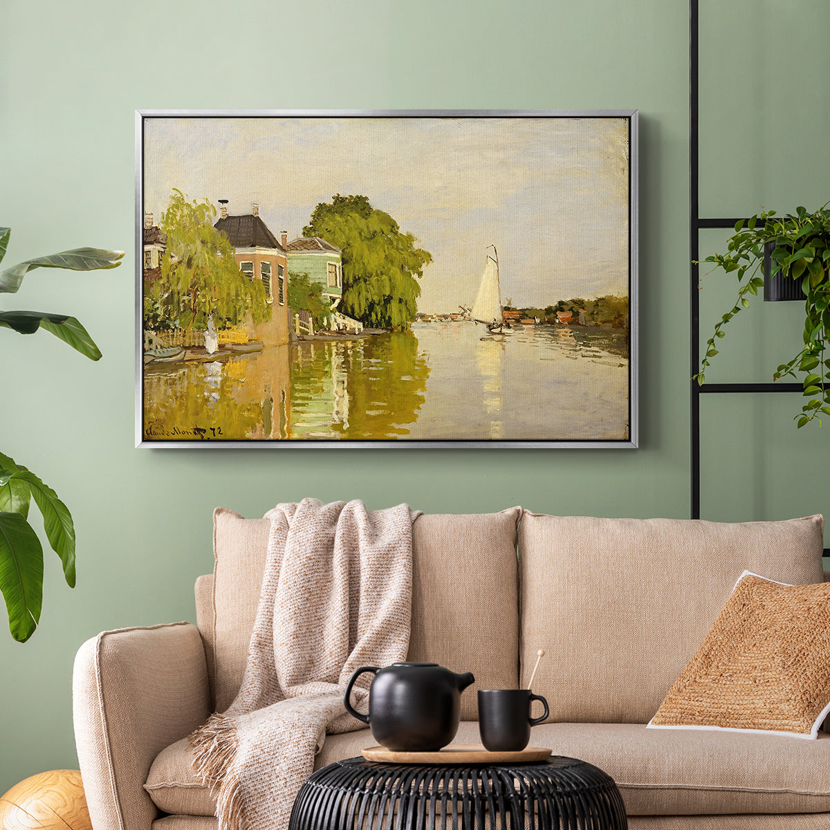 Silver floater framed canvas featuring a peaceful village scene with houses bordering water, displayed above a sofa in a modern living room.