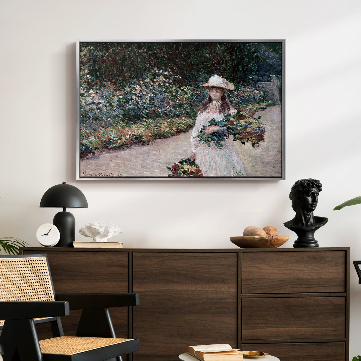 Young Girl in the Garden at Giverny, 1888 by Claude Monet displayed in a silver floater framed canvas above a dark wood credenza in an entryway.