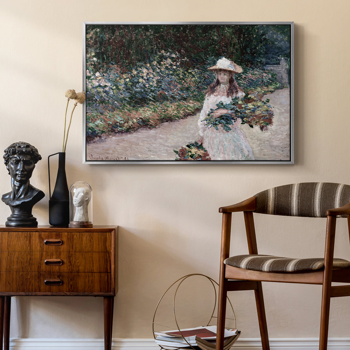 Young Girl in the Garden at Giverny, 1888 by Claude Monet as a silver floater framed canvas featuring a figure resting in colorful garden under soft light, styled above a mid-century console in a contemporary living area.