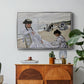 On the Beach at Trouville, 1870 by Claude Monet in a silver floater framed canvas featuring figures seated on beach with parasols facing the ocean, displayed above a wood console cabinet.